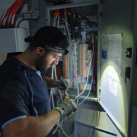 Emergency Electrician carrying out emergency switchboard repairs for an industrial client