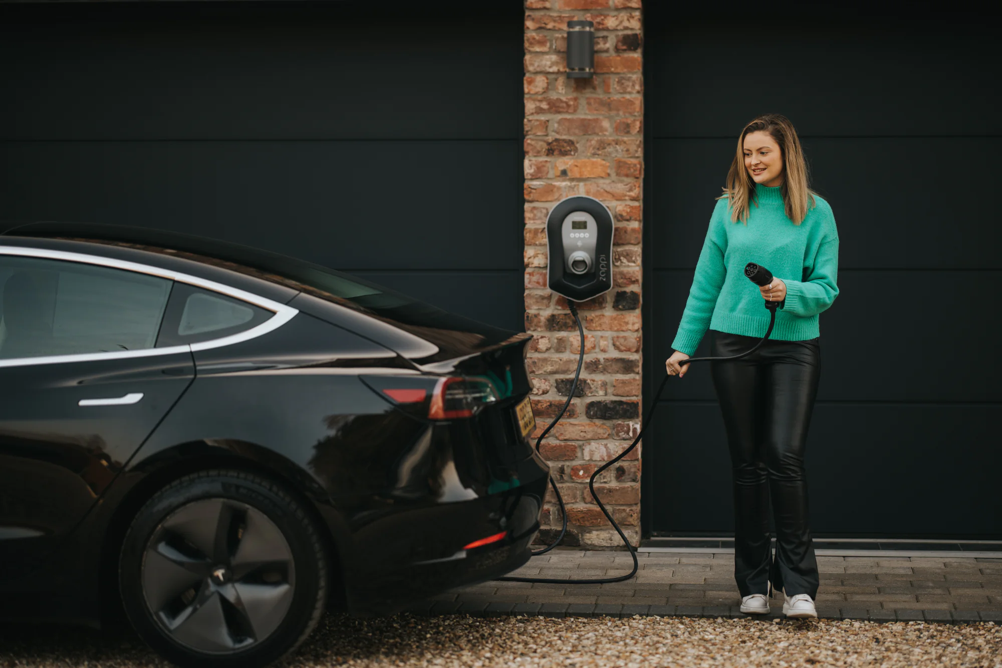 Woman charging her electric vehicle at home